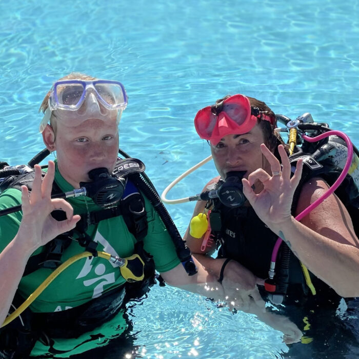 Instructor with child scuba diving in swimming pool